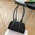 Elegant black lychee leather pillow bag with silver hardware on a golden mesh chair - Black