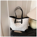 Detail of white embossed tote bag with black bow patterns and golden heart charm - White