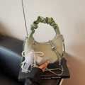 Green woven hobo bag with pearl lace bow and silver chain strap on black leather sofa - With Charm / Green