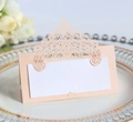 Detail of laser-cut wedding name place card with hollow crown pattern on a dinner plate - Jade Pearl