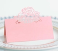 Pink laser-cut rose place card for weddings, set on a decorative white and gold dinner plate - Pink
