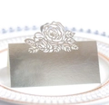 Gros plan d'un marque-place argenté découpé au laser avec motif de rose sur assiette - Argent Réfléchissant