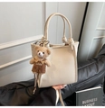 Dettaglio borsa bianca in pelle martellata con nodi ai manici e ciondolo a orsetto - Beige Con Ciondolo