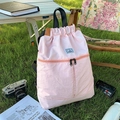 Light pink waterproof nylon drawstring backpack in an outdoor camping grass setting - Pink