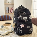 Detail of black quilted backpack featuring sweet bow patches and plush star charm accessory - With Charm / Black