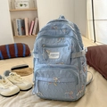 Detail of light blue nylon backpack featuring colorful bow embroidery and side buckles - With Charm / Blue