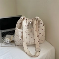 Beige tote bag with red bow print and drawstring closure on a desk with laptop - Rice White (No Pendant)