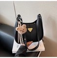 Close-up of black leather underarm bag with gold logo plaque and plush bear charm - With Charm / Black
