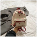 Detalle de mini mochila crema con estampado de lazos rojos y cremalleras doradas - Blanco