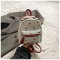 Detalle de una mini mochila blanca con lazos rojos y lunares sobre un blazer elegante - Azul