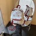 Mini light blue backpack with red bow prints and leather straps shown in mirror view - Blue