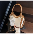 Detail der cremefarbenen Beuteltasche mit braunem Rand und dekorativem Perlenanhänger - Weiß