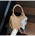 Detail der beigen Beuteltasche mit Litschi-Struktur, Perlenanhänger und Spitzenschleife - Khaki