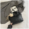 Detail of black crocodile texture handbag with plush bear charm and tassel on a suit - Black With Pendant