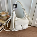Detail of a large cream glossy patent leather tote bag with a buckle pocket and wide strap - White