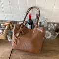 Macro detail of brown leather tote bag texture with tassel and T-letter pendant - With Charm / Brown