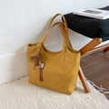 Gros plan du sac fourre-tout jaune vif en similicuir texturé avec détail de pompon - Avec Pendentif / Jaune