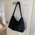 Detail of black canvas messenger bag featuring a large front flap pocket and wide strap - Black