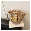 Close-up of woven straw tote bag with Hello embroidery and leather handles on books - Yellow