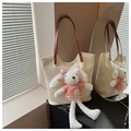 Détail du sac cabas tissé crème avec un charmant lapin en peluche et des anses en cuir brun - Blanc Cassé