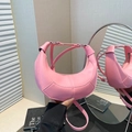 Sac demi-lune rose minimaliste en similicuir grainé porté par un mannequin à la main - Rose