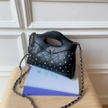 Close-up of a black quilted leather crossbody bag with silver bow and crystal accents - Black