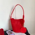 Detail of red suede bucket bag featuring knotted handle and minimalist round pendant - Red
