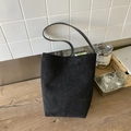 Bolso cubo minimalista de ante negro con correa larga al hombro en ambiente moderno - Negro