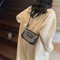 Détail du sac bandoulière à damier gris avec garniture noire sur un trench-coat beige - Noir
