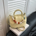 Borsa a secchiello giallo lime a pieghe con catena di perline colorate su un libro - Giallo