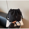 Detalle de bolso tipo saco negro con cordón, logo SHUNUO y correa bandolera - Negro