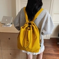 Sac à dos jaune minimaliste avec cordon de serrage et texture nylon en scène de vie - Jaune