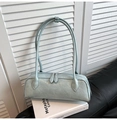 Detail of mint green baguette bag with pleated texture and double zippers on a white book - Blue