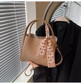Détail du sac seau abricot en cuir grainé avec une poignée ornée d'un foulard en soie - Kaki