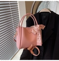 Pink lychee grain bucket bag featuring a decorative checkerboard silk scarf and gold hardware - Pink