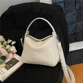 Chic beige lychee textured leather handbag with silver hardware on a black seat - White