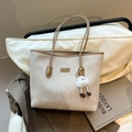 Bolso tote vintage grande en beige con correas marrones y colgante de peluche en silla - Caqui