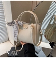 Détail du sac seau blanc cassé avec texture litchi, nœud à carreaux et détails dorés - Blanc
