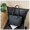 Detalle de bolso tote de nailon negro con solapa de cuero, logo grabado y cierre magnético - Negro