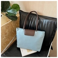 Detalle del bolso tote de nailon azul claro con solapa de cuero marrón y logo CLEARDK en silla - Azul