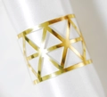 Detail of golden geometric napkin ring with hollow triangular laser cut pattern on white satin - Reflective Gold