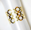 Macro view of reflective gold hollow napkin ring on white satin fabric for party decor - Reflective Gold