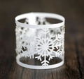 Macro shot of white laser-cut snowflake napkin ring on elegant dark wood table - White