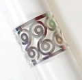 Detail of silver hollowed-out napkin ring with spiral geometric design on white fabric - Reflective Silver