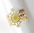 Close-up of golden snowflake napkin ring with intricate cutout design for table decor - Reflective Gold