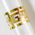 Elegant gold metal napkin ring with hollow geometric pattern on white silk background - Reflective Gold