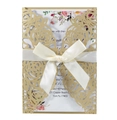 Macro detail of laser-cut rose patterns on gold card with satin ribbon and invitation insert - Beige Gold