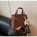 Détail du sac seau en cuir marron motif litchi avec porte-clés chien en peluche - Marron