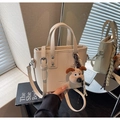 Détail du sac seau blanc crème avec texture cuir grainé et pendentif chien en peluche - Blanc Cassé