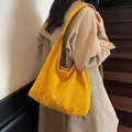 Minimalistische große Tote-Bag aus gelbem Kunstleder getragen von einem Modell in Beige - Gelb